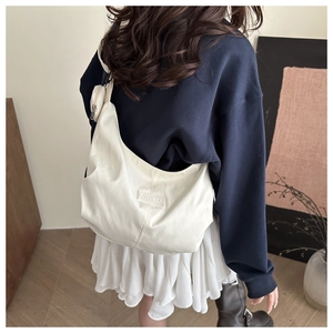 Modella che indossa una borsa tote in tela color crema con portamonete rotondo staccabile