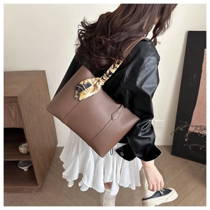 Brown leather tote bag featuring a decorative patterned silk scarf wrapped on the handle