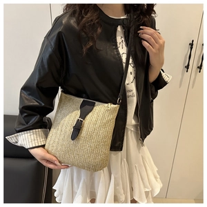 Detail of the woven straw crossbody bag with black leather trim and golden buckle