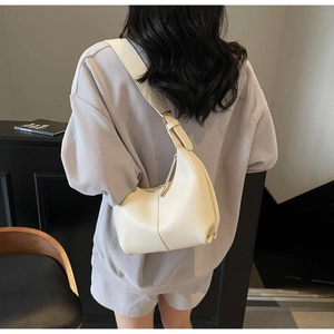 Rear view of a model wearing the cream crescent tote bag with adjustable wide strap