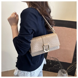Detail of khaki woven leather shoulder bag with textured finish and golden U-shaped clasp