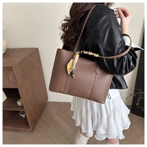Brown tote bag with decorative floral scarf on a model in a cozy vintage library