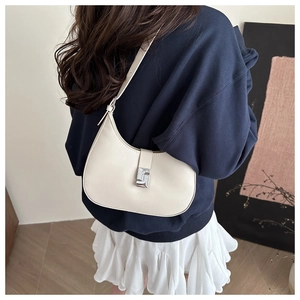 Detail of a creamy white half-moon shoulder bag with a stylish silver metal buckle