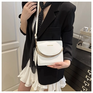 Close-up of a white leather crossbody bag with gold chain and matching mini pouch