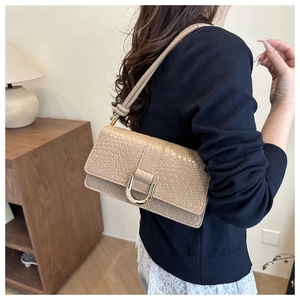 Detail of beige shoulder bag with crocodile texture and gold U-shaped metal buckle