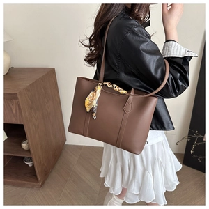 Detail of dark brown tote bag with decorative yellow silk scarf on the handle