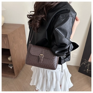 Detail view of deep brown woven texture square shoulder bag with golden buckle buckle detail