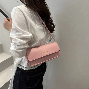 Pink rectangular leather underarm bag with gold lettering shown on a model's shoulder