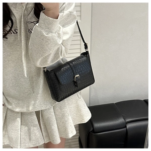 Detail shot of black woven texture crossbody bag with gold buckle closure for women