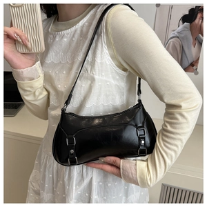Detail view of glossy black faux leather baguette bag with silver buckles and retro straps