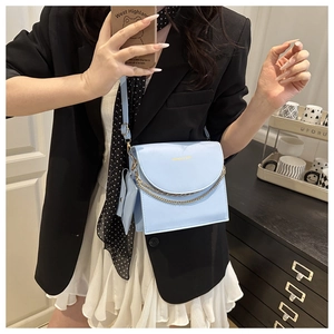 Close-up of light blue flap square bag with gold chain and matching mini pouch