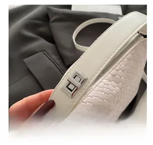 Détail du sac bandoulière blanc tressé montrant le fermoir argenté et la texture