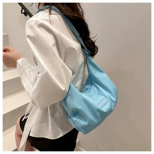 Detailed side view of light blue nylon crossbody bag featuring the Fanyissa logo label
