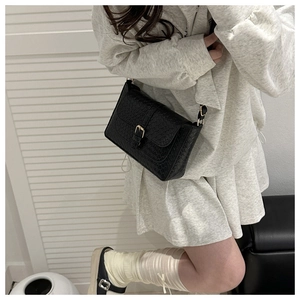 Detail of black woven texture square bag with gold buckle and adjustable strap