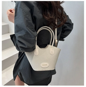 Detailansicht der elfenbeinfarbenen Beuteltasche mit Textur und goldenem Fashion-Label