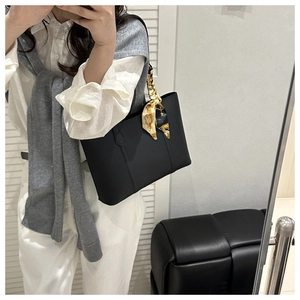 Detail of black tote bag with luxury silk scarf handle and elegant leather texture