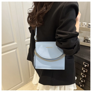 Detail of light blue crossbody bag with gold chain and Fashion & Bags text on leather