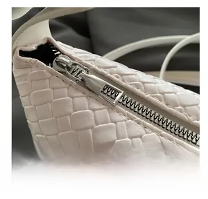 Détail de la fermeture éclair en métal argenté sur un sac à main tissé crème