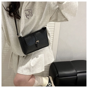 Close-up of black faux crocodile leather shoulder bag with gold buckle detail