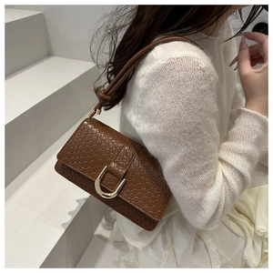 Close-up of brown woven texture handbag with golden U-shaped buckle on female model
