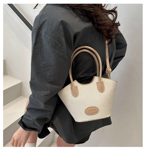 Detail der gewebten Stroh-Eimertasche mit Ledergriffen und Modeetikett in Creme