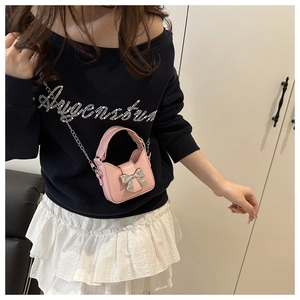 Pink mini crossbody bag with silver bow accent and metal chain strap on model