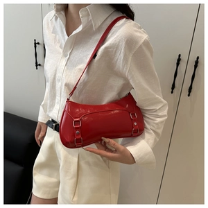 Detail of red patent leather shoulder bag with silver hardware worn by a model
