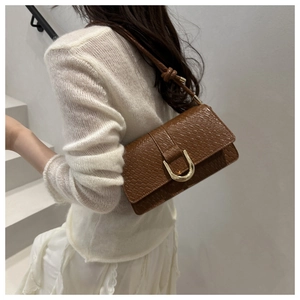 Detail of vintage brown crocodile embossed shoulder bag with golden U-shaped buckle closure