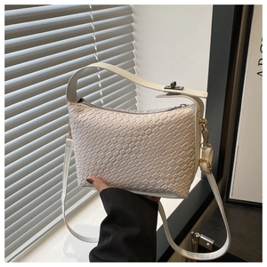 Détail du sac tressé avec bandoulière réglable et finitions en bronze élégantes