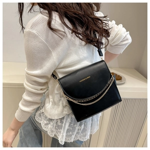 Detail of black leather crossbody bag with gold chain strap and FASHION lettering