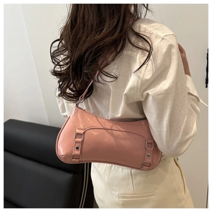 Dettaglio della borsa a spalla baguette rosa lucida con fibbie metalliche e borchie chic