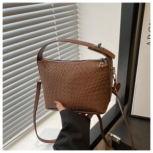 Détail d'un sac à main marron tressé avec boucle métallique et fermeture éclair argentée