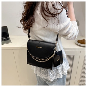 Detail of black crossbody square bag with gold chains and mini charm pouch pendant