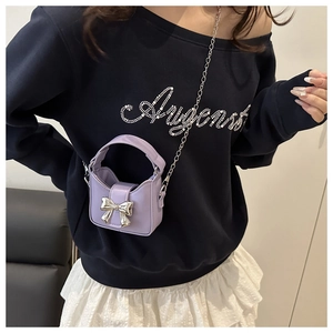 Gros plan d'un mini sac bandoulière lavande avec chaîne argentée porté par un modèle