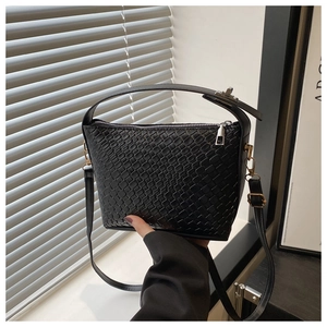 Gros plan sur la texture tressée noire d'un sac à main moderne avec fermeture éclair