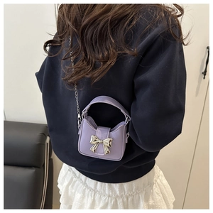 Détail d'un mini sac en cuir verni lavande avec nœud argenté et bandoulière chaîne