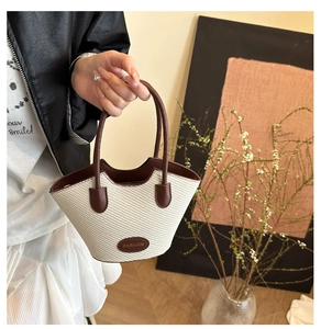 Detailed close-up of fashion woven bucket bag with leather handles and chic oval emblem