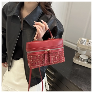 Detail of red box bag showing pebbled leather and tweed texture with fringe zippers