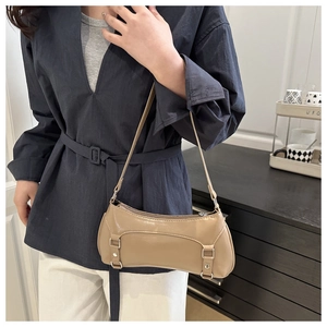 Detail of light khaki glossy baguette bag with silver buckles shown on shoulder