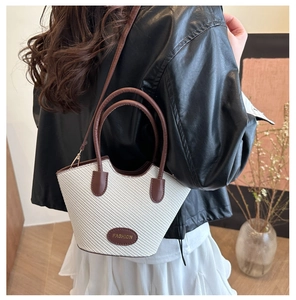 Detail der weißen geflochtenen Trapez-Beuteltasche mit braunem Rand und Tragegurt