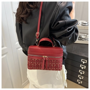 Detail of red tweed and PU leather box bag with gold hardware and tassel zipper pull