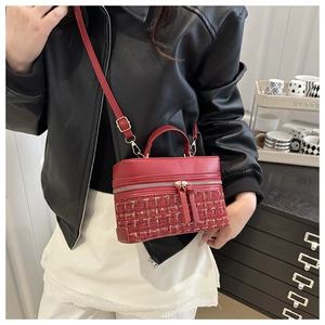 Détail de la texture patchwork en tweed rouge et similicuir sur un sac à bandoulière vintage
