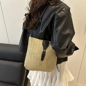 Woven straw crossbody bag with black leather trim and metal buckle for beach vacation