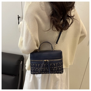 Detail of tweed and leather patchwork bucket bag with gold zipper and long tassels