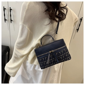 Détail du sac bandoulière en tweed bleu marine avec garnitures dorées et poignée en cuir