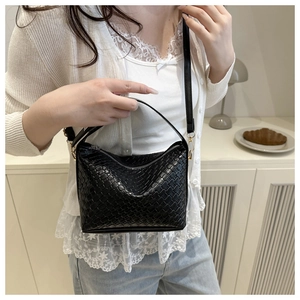 Détail du sac bandoulière tissé noir avec texture croisée et forme en demi-lune