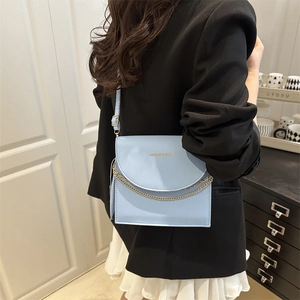 Light blue square crossbody bag with gold chain and fashion logo shown on model