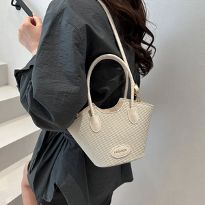Sac seau tissé beige chic avec plaque fashion présenté dans un décor minimaliste