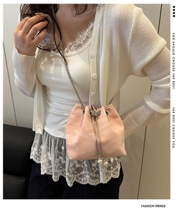 Detail of pink mini bucket bag with chain strap, pearl drawstrings and butterfly ornament