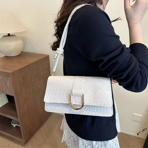 White woven leather crossbody bag with gold horseshoe buckle on female model